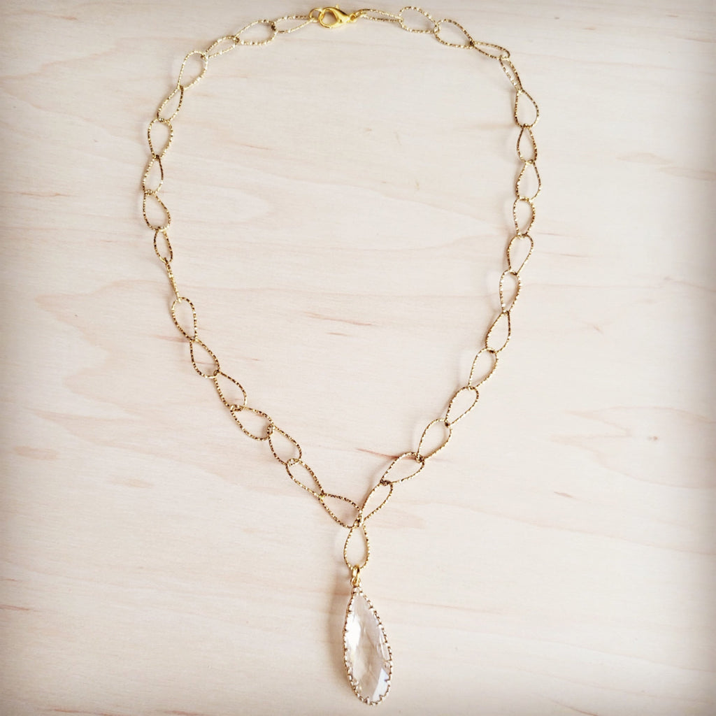 Gold-tone chain necklace with textured oval links and a single faceted clear teardrop pendant.