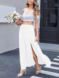 A woman wearing a white tiered maxi skirt with a side slit and drawstring waist, standing outdoors.