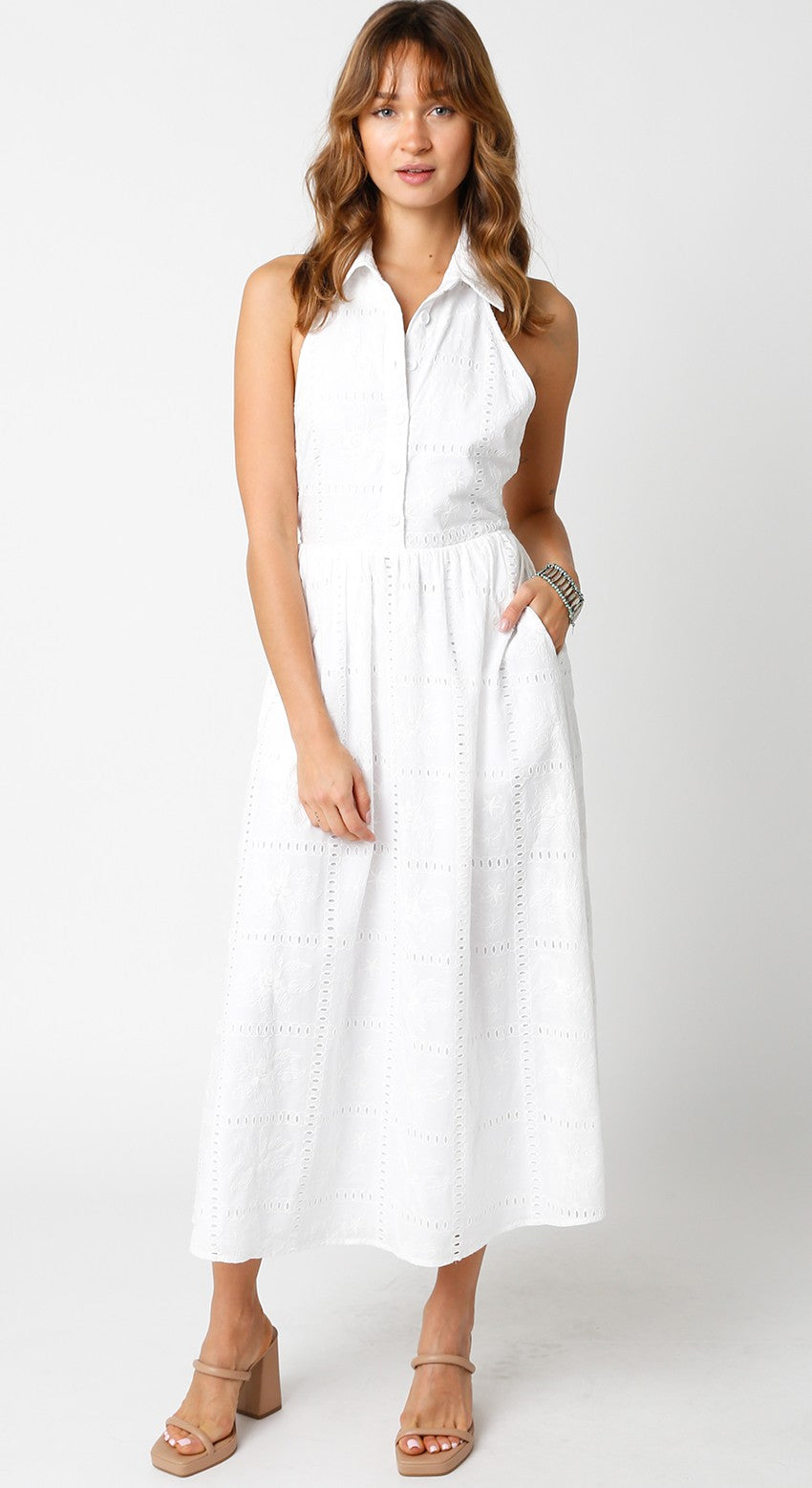 Model wearing a white sleeveless midi dress with a collar, eyelet fabric, and open back detail