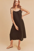 Woman wearing a soft cotton gauze midi cami dress with braided tie shoulder straps and side pockets