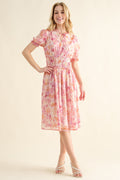 Woman wearing a vibrant printed midi dress with a smocked waist and fluttery sleeves.