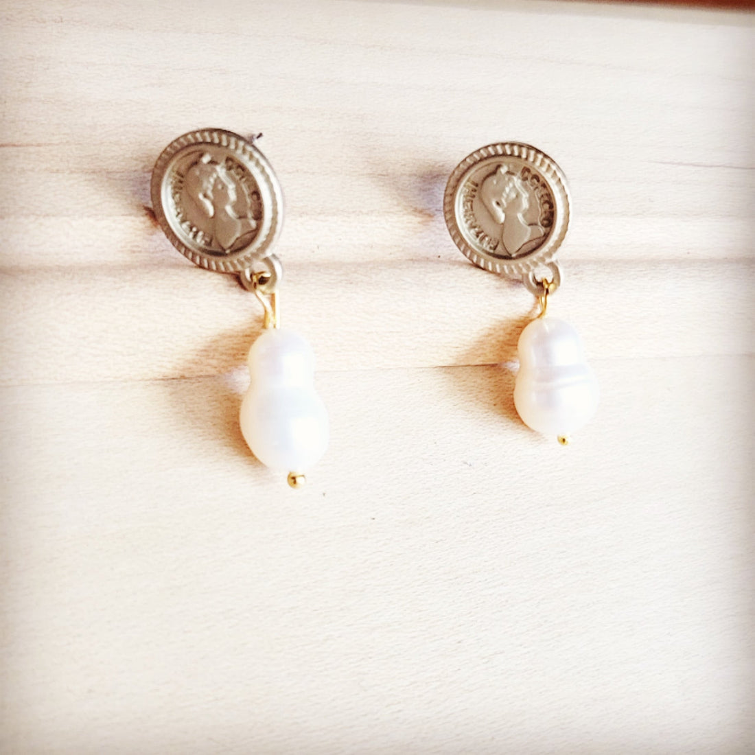 Matte gold coin stud earrings with dangling baroque freshwater pearls on a wooden background