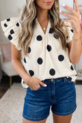 Woman wearing a classic polka dot V-neck shift blouse with ruffle sleeves in cream and black