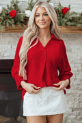 Woman wearing a Red Collared V-Neck Smocked 3/4 Sleeve Tunic Blouse with white shorts, in front of a fireplace decorated for holidays.