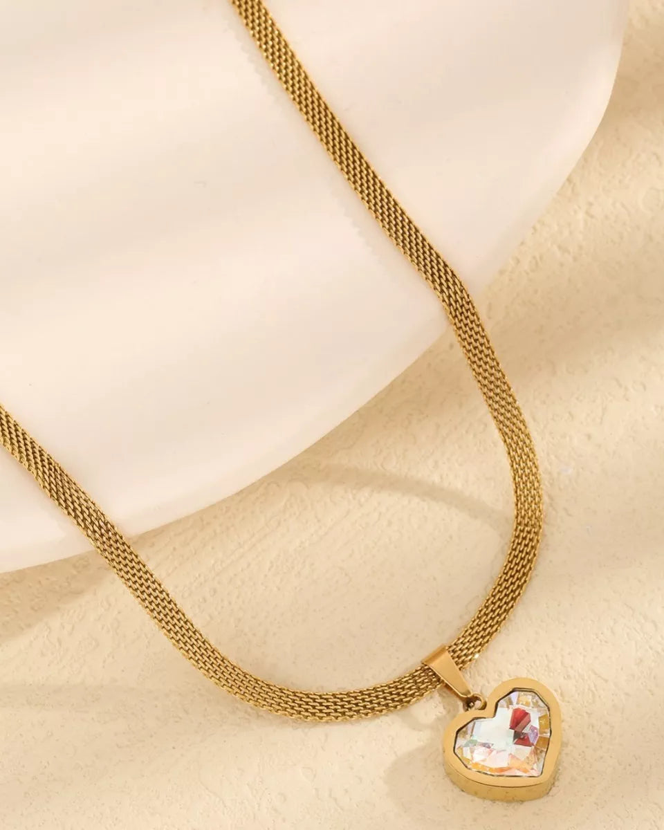 Gold necklace with a heart-shaped pendant on a beige background