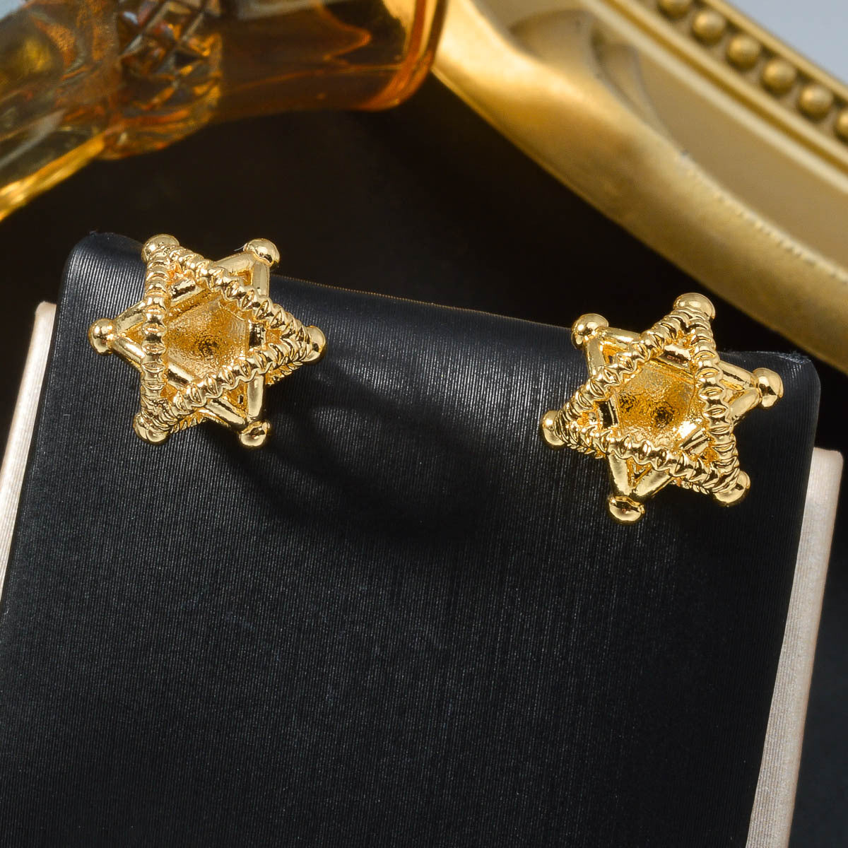 A pair of gold-plated minimalist hollow star stud earrings on a white background.
