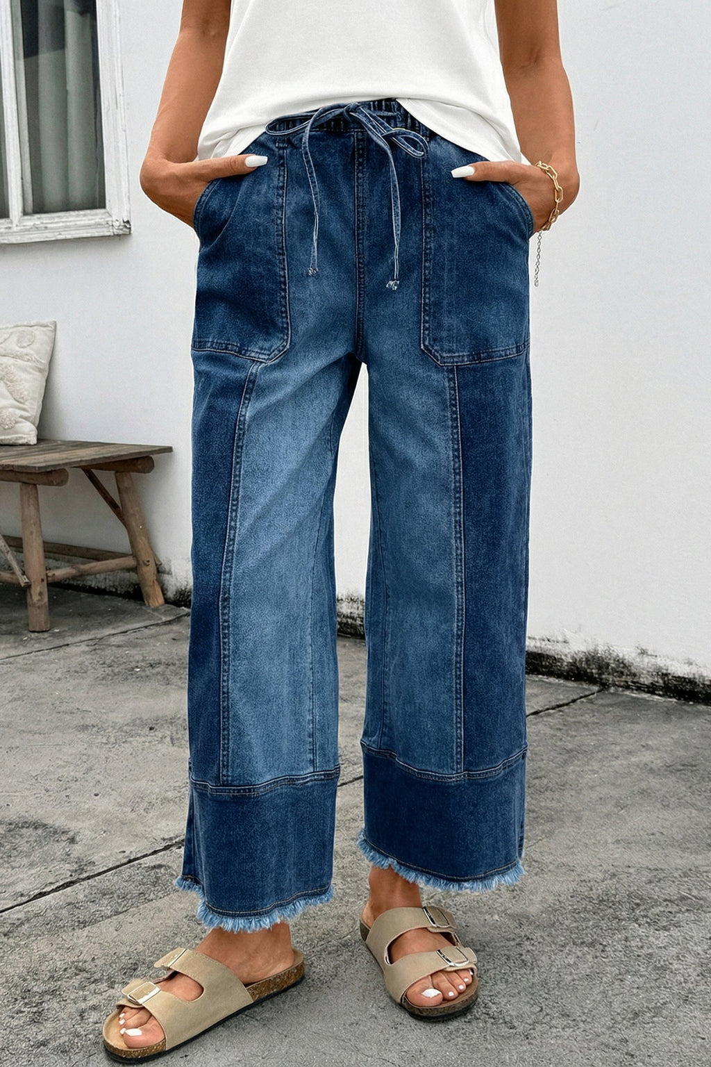 Woman wearing Aleah high-waisted wide-leg blue denim pants with raw hem detail and drawstring waist