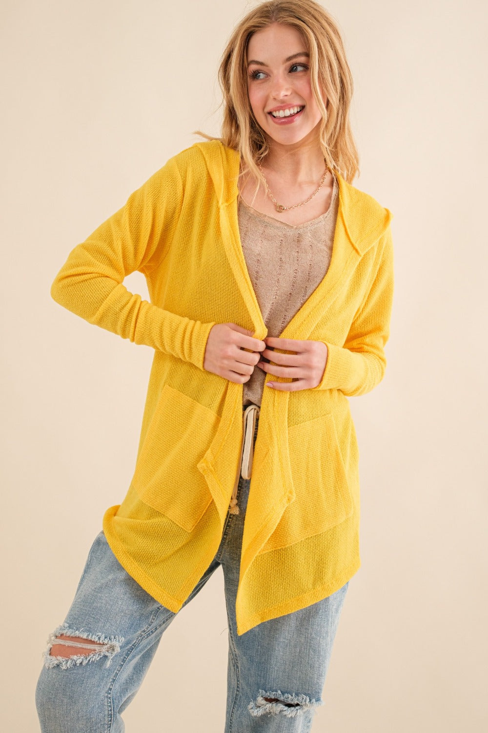 Model wearing a bright yellow thermal knit hooded open front cardigan with two large front pockets