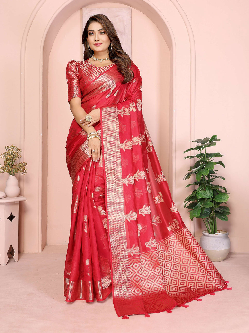 A beautiful red soft organza silk saree featuring intricate weaving patterns and a matching blouse piece.