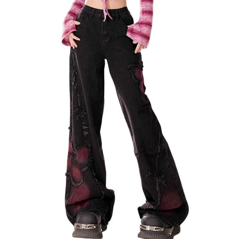 Full shot of washed black wide leg distressed denim pants with red butterfly patterns and high waist, styled with chunky platform shoes.