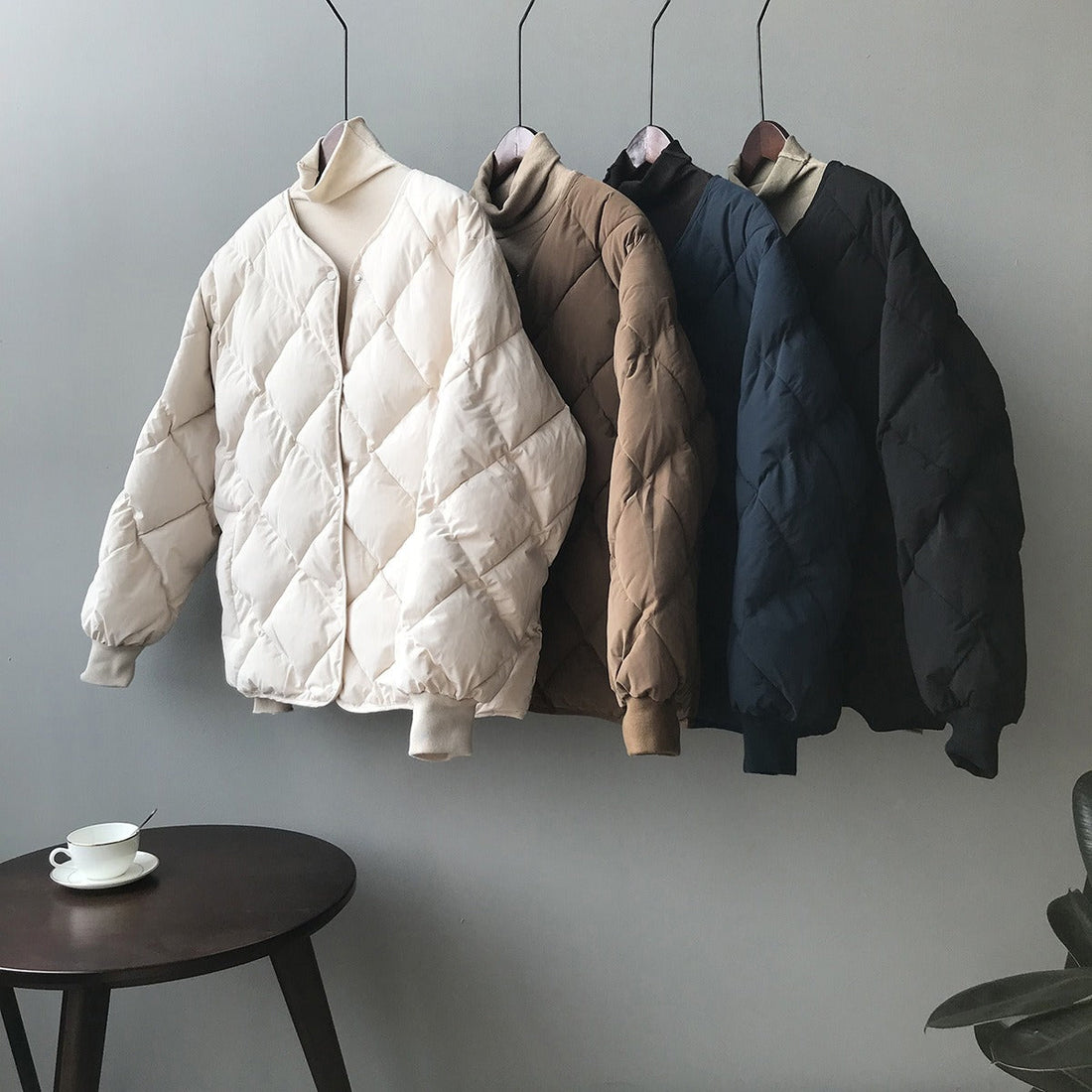Four Harajuku Style Quilted Puffer Jackets in beige, brown, dark blue, and black hanging against a grey wall, with a close-up of the brown jacket worn by a model.