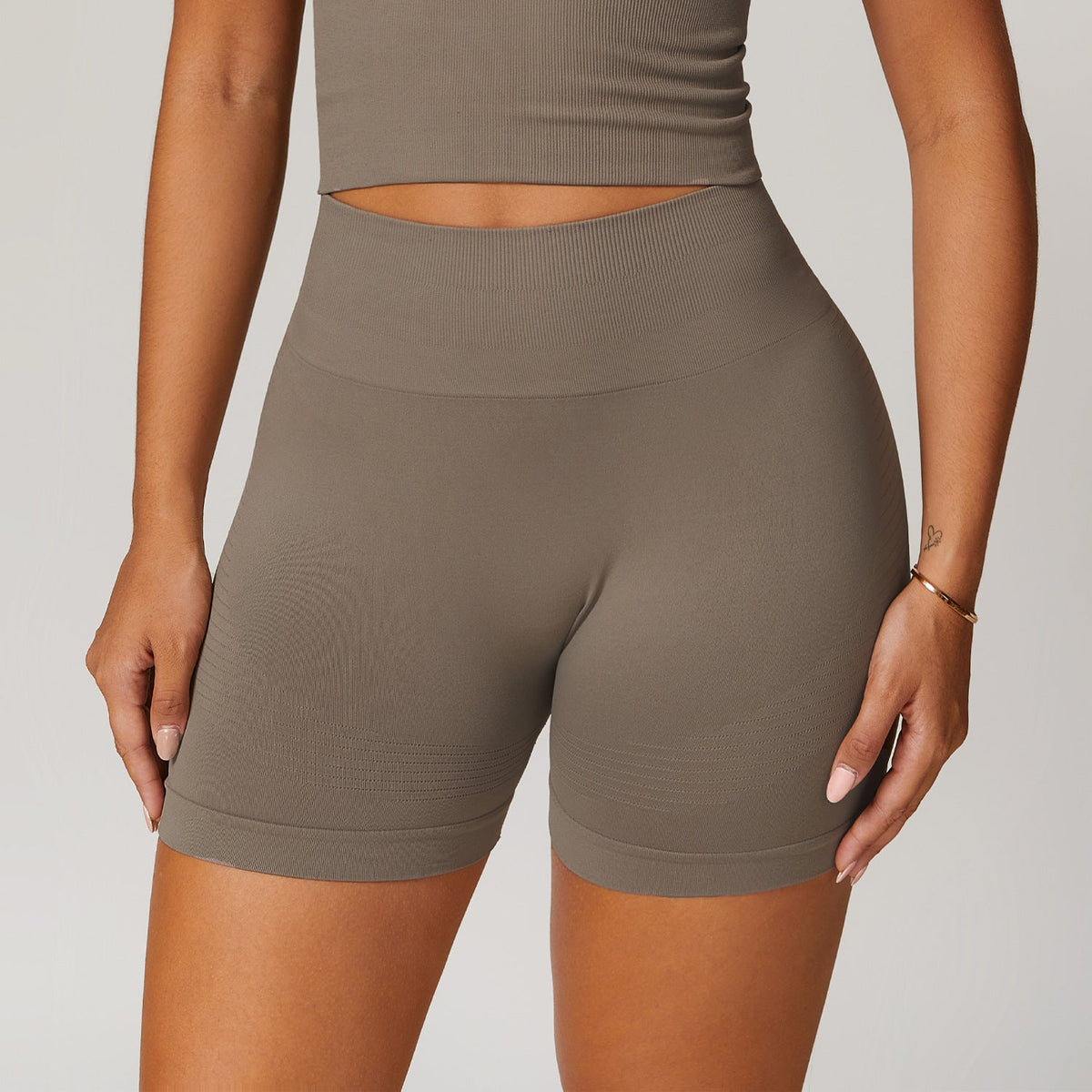 Model wearing high-waist tight yoga shorts in plum, showing a flattering sporty fit.