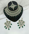 Green stone work necklace and earring set on a neutral background