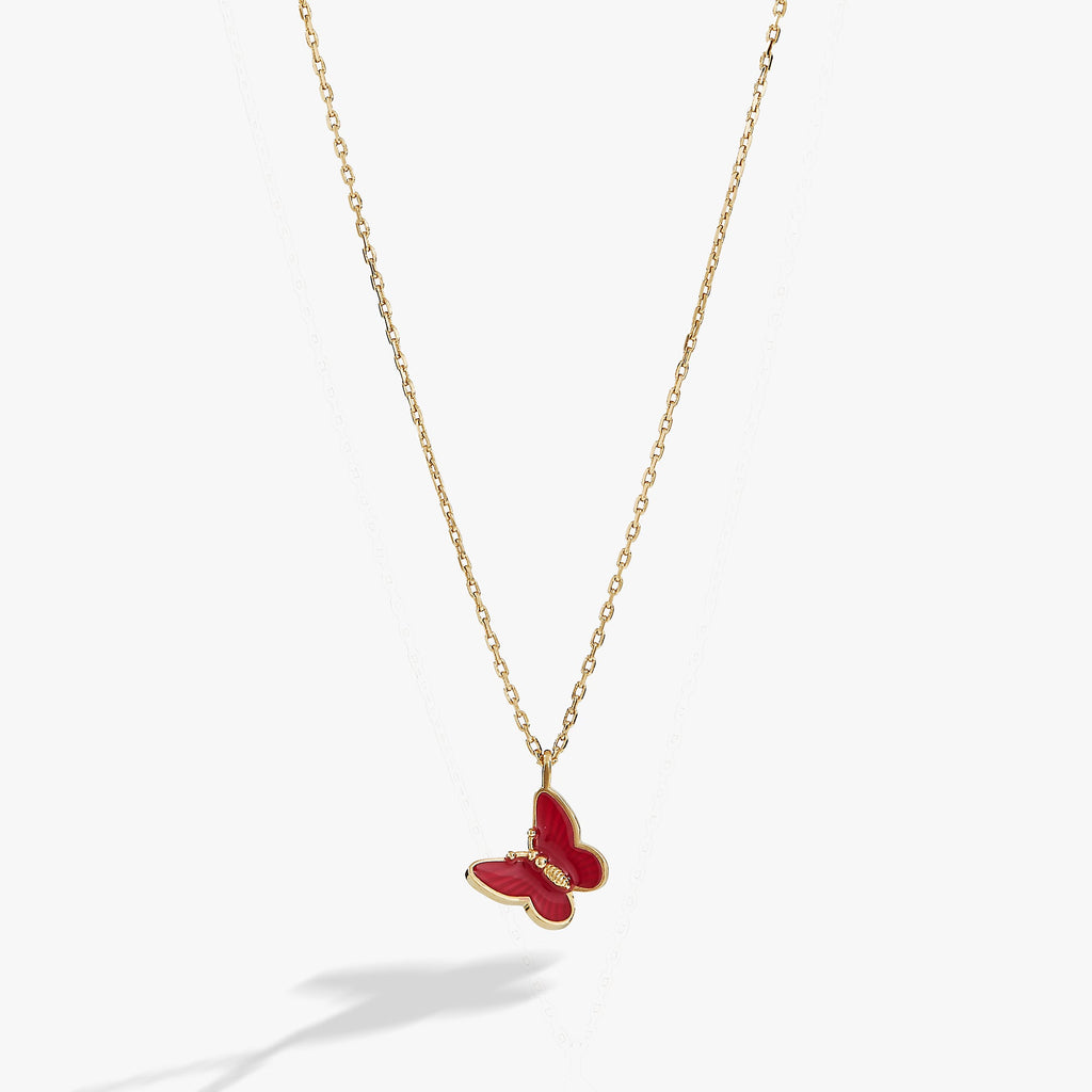 Close-up of a mini pink enamel butterfly pendant on a shiny gold adjustable chain.