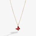 Close-up of a mini pink enamel butterfly pendant on a shiny gold adjustable chain.