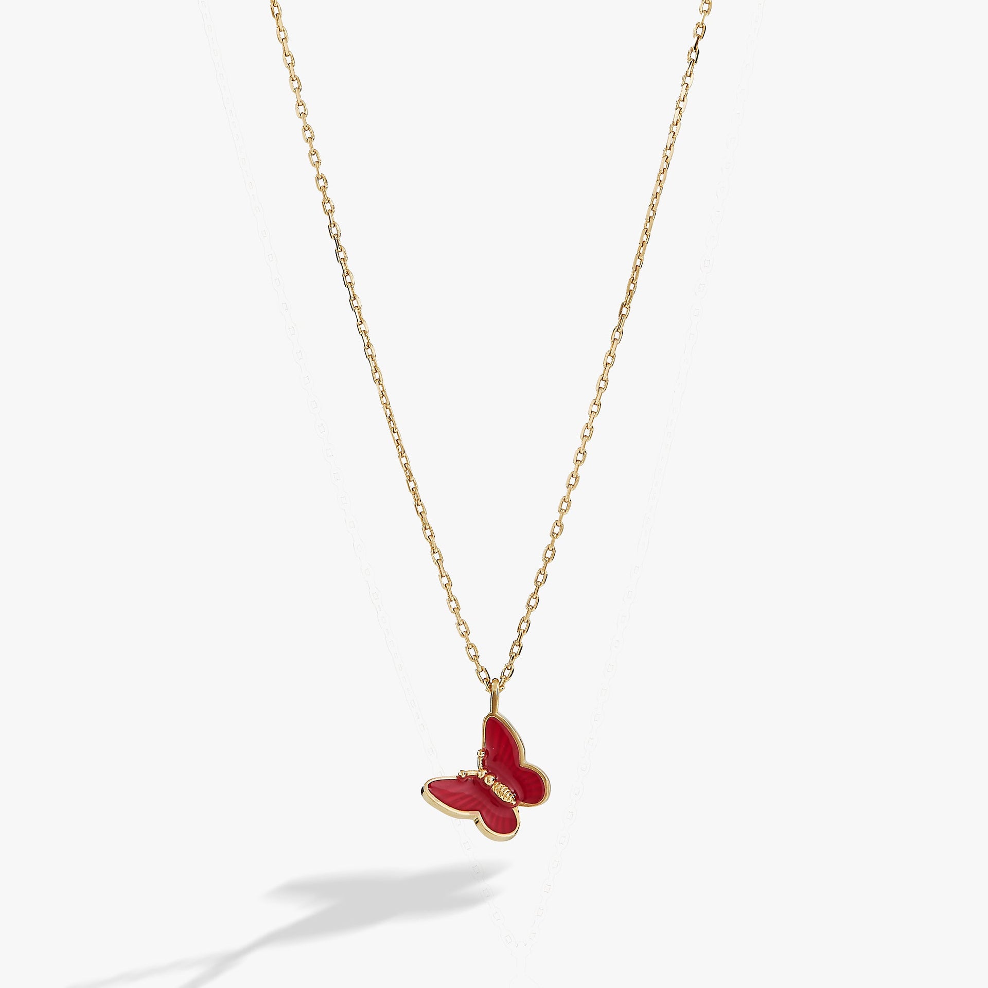 Close-up of a mini pink enamel butterfly pendant on a shiny gold adjustable chain.