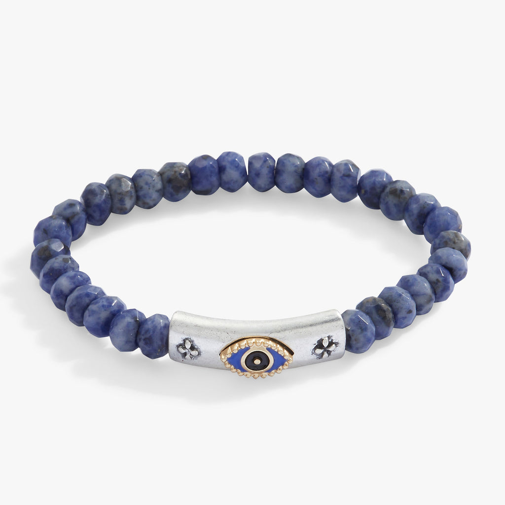 Close-up of a two-tone evil eye charm bracelet with faceted blue Sodalite-colored glass beads on a stretch band.