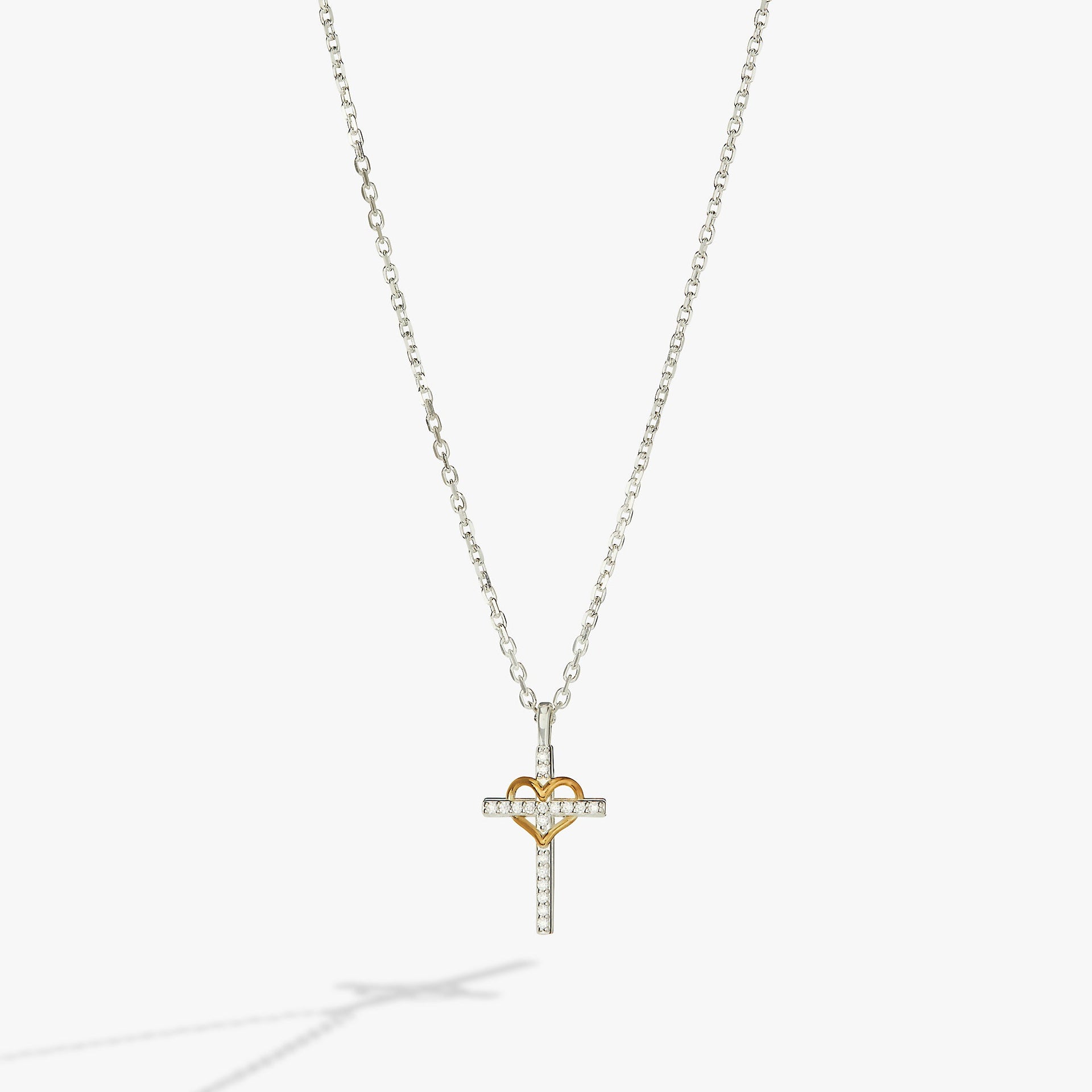 Crystal-encrusted silver cross and gold-plated heart pendant necklace on an adjustable sterling silver chain.