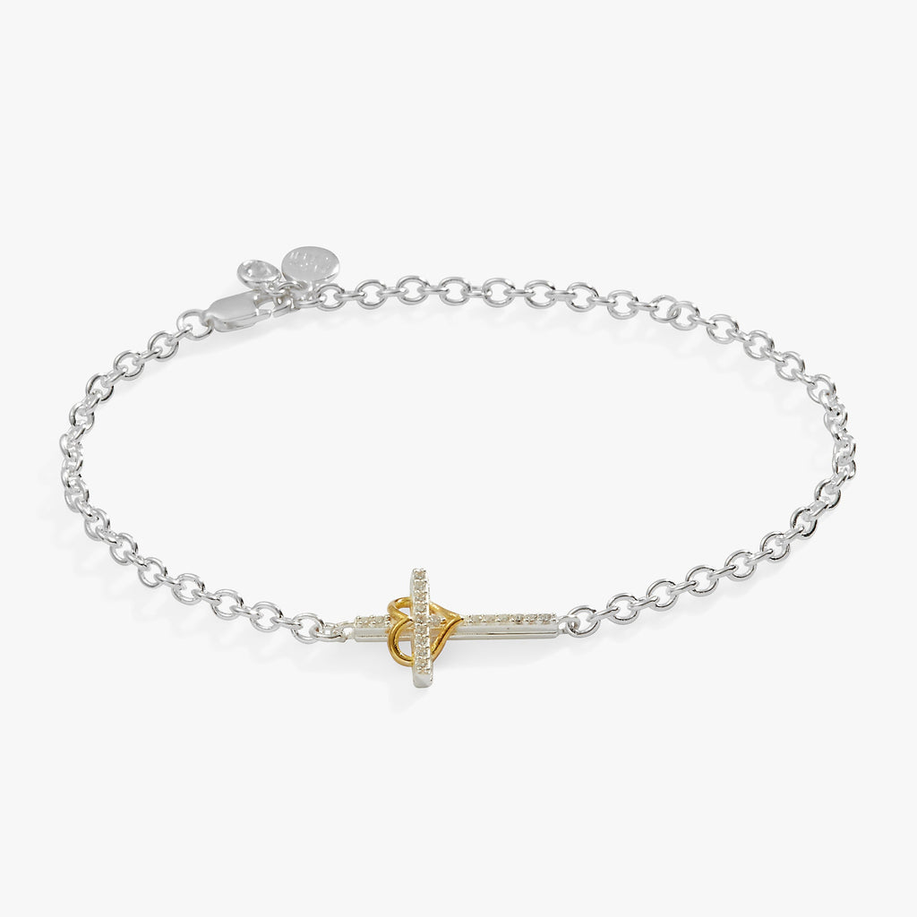 Close up of an adjustable Sterling Silver bracelet featuring a crystal-encrusted cross and a gold-plated heart charm.