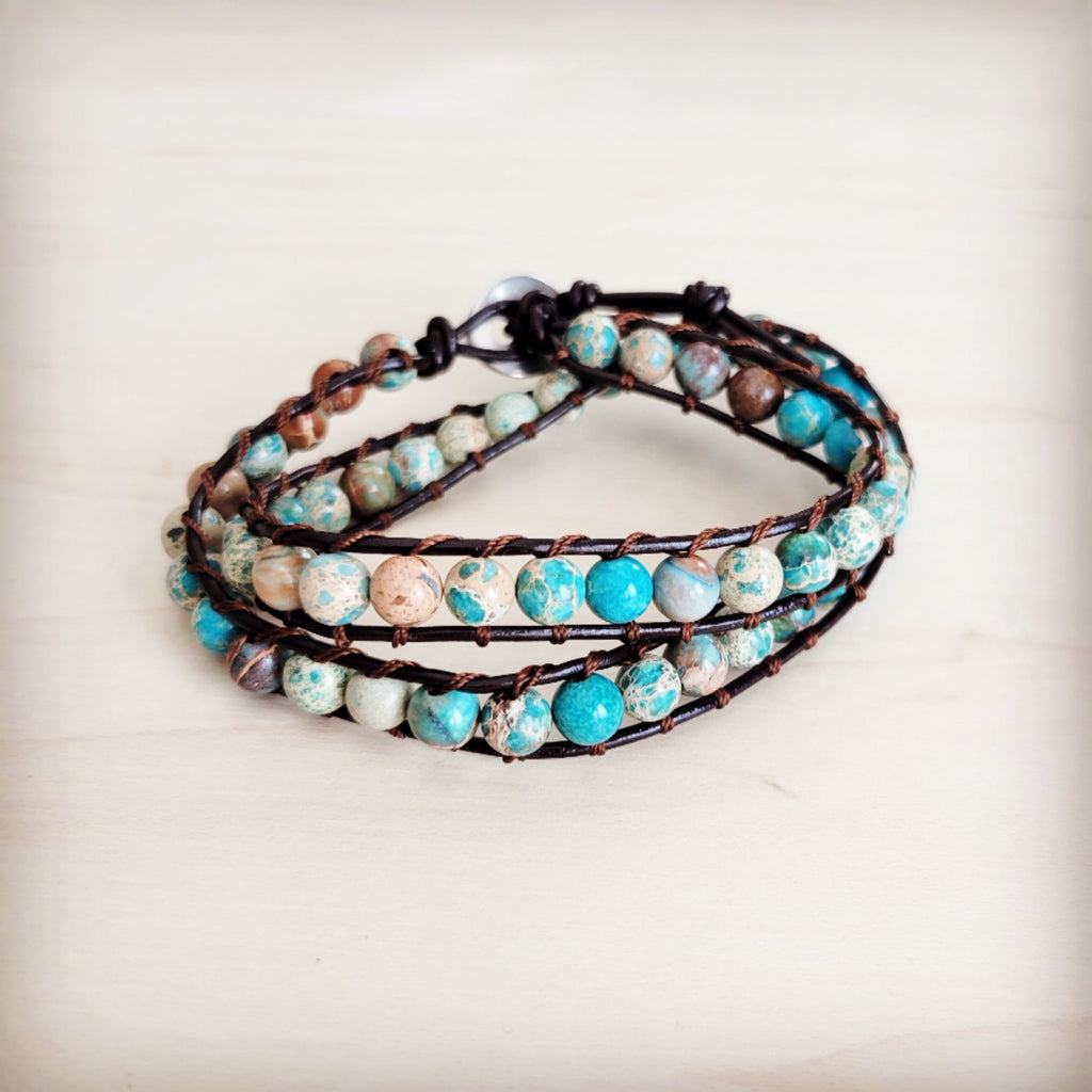 Double wrap bracelet featuring blue and earth-toned Imperial Jasper beads on a dark leather cord worn on a wrist