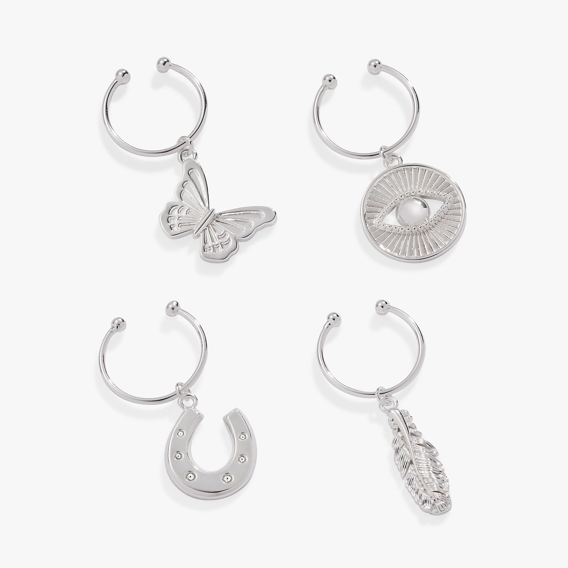 Set of 4 wine glass charms featuring butterfly, feather, evil eye, and horseshoe symbols on stemless wine glasses.