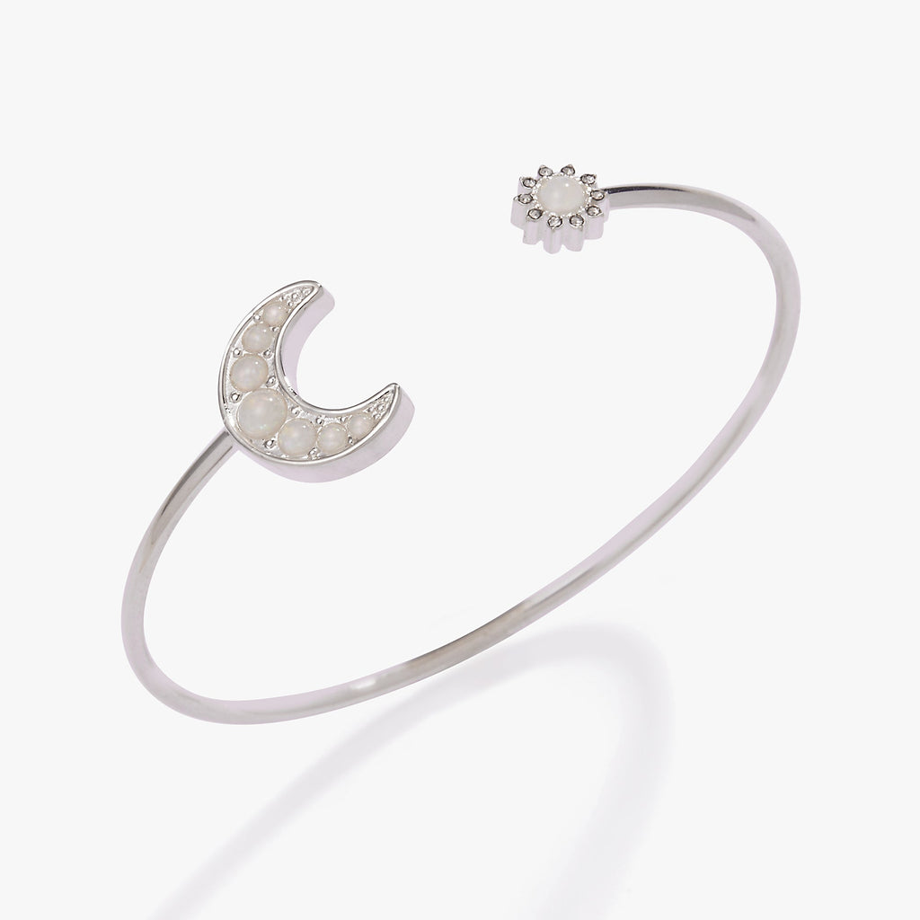 Silver open cuff bracelet featuring a crescent moon on one end and a sun motif on the other.
