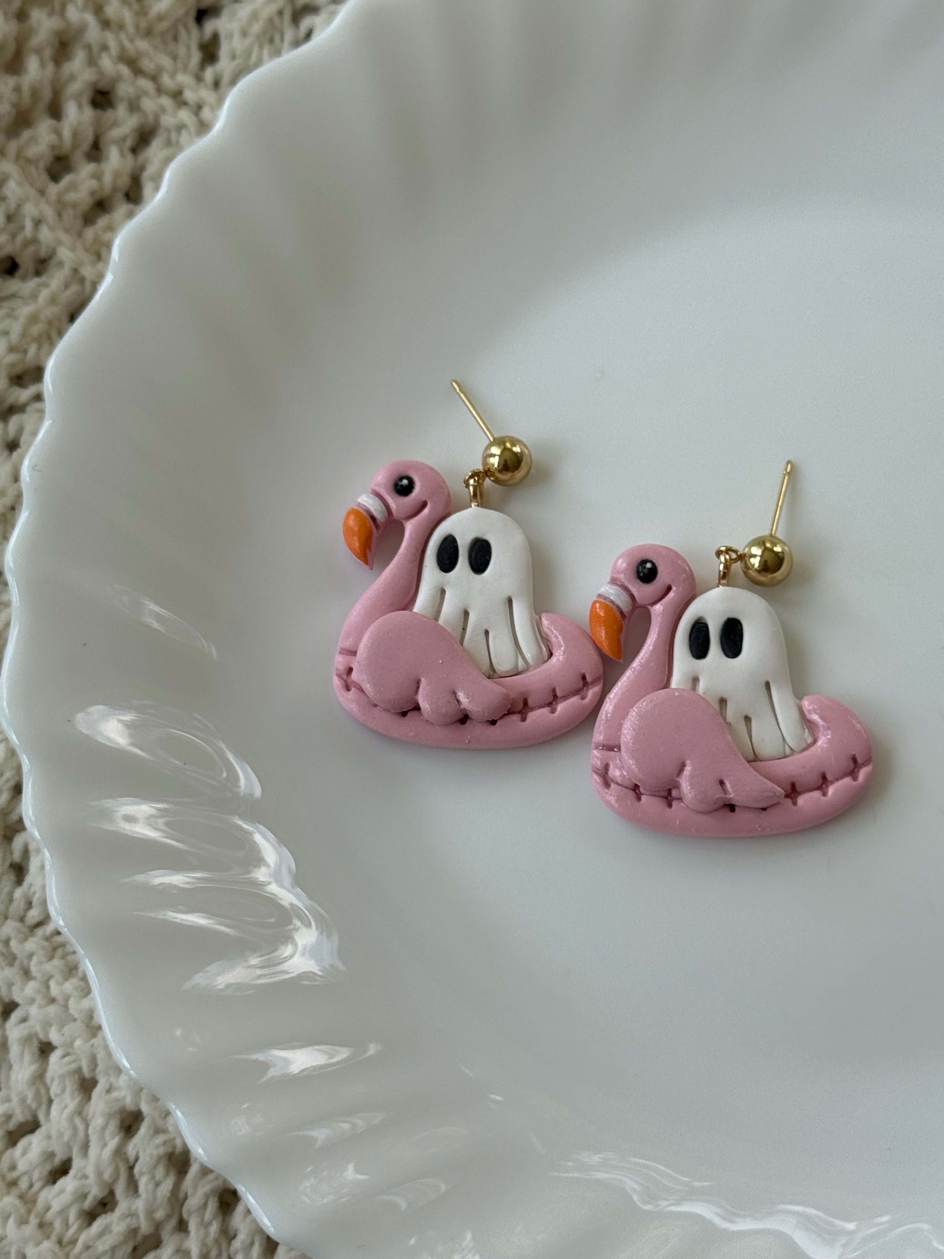 A pair of handmade Pink Float Ghost earrings dangling from 14k gold hooks