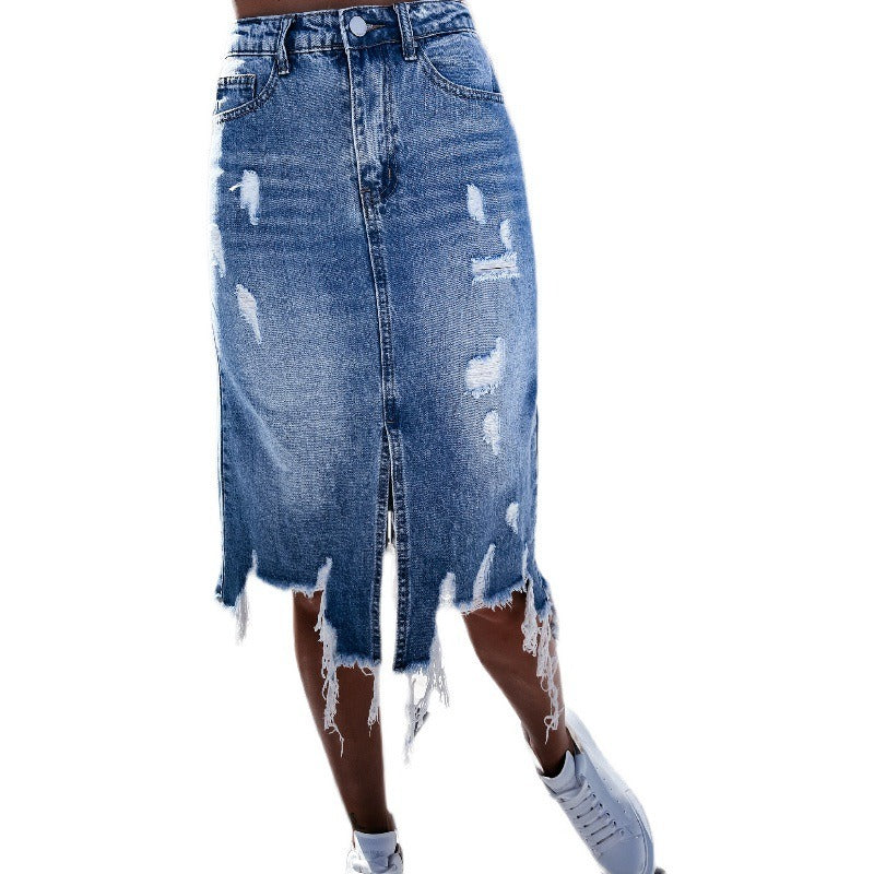 A woman wearing a blue ripped denim midi skirt with a raw, tasseled irregular hem, styled for street fashion.