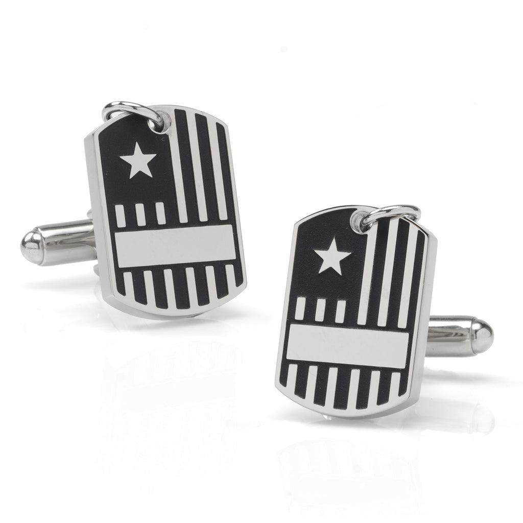 Close up of silver-tone military dog tag style cufflinks with flag design worn on a white dress shirt cuff.