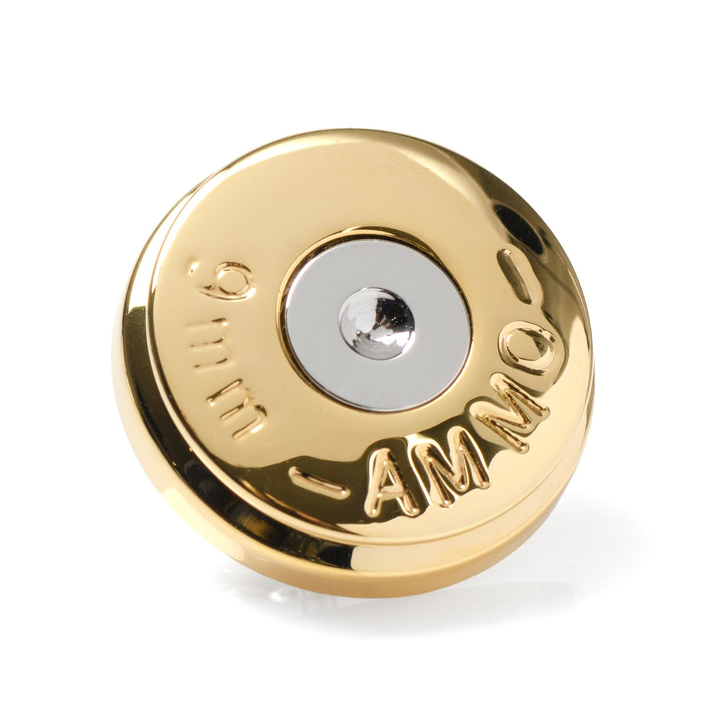 Close up of a 9mm bullet shell lapel pin in gold and silver metal tone on a black suit lapel