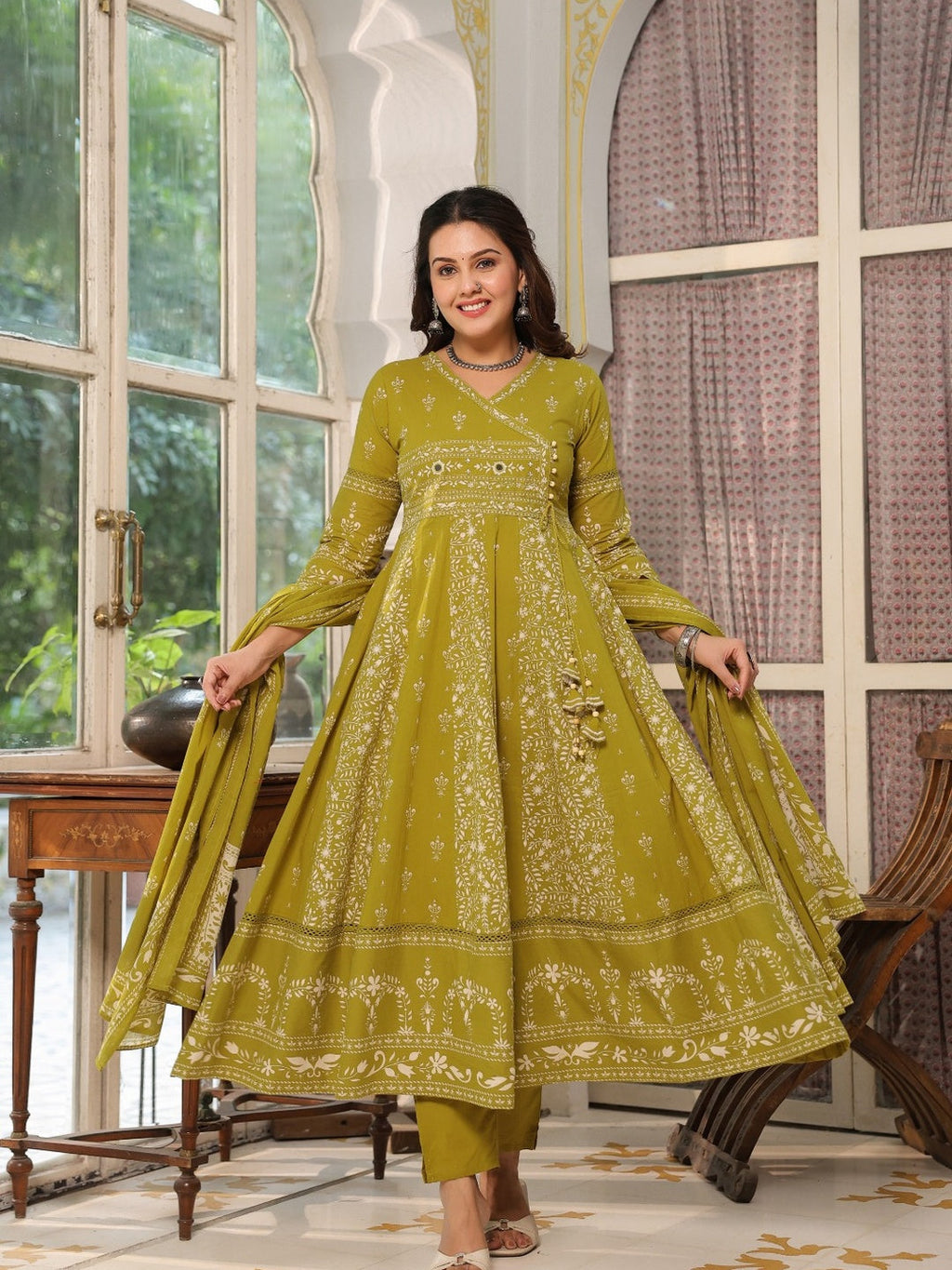 Woman wearing an olive floral jaal printed cotton Angarkha style Anarkali kurta set with matching pants and dupatta.