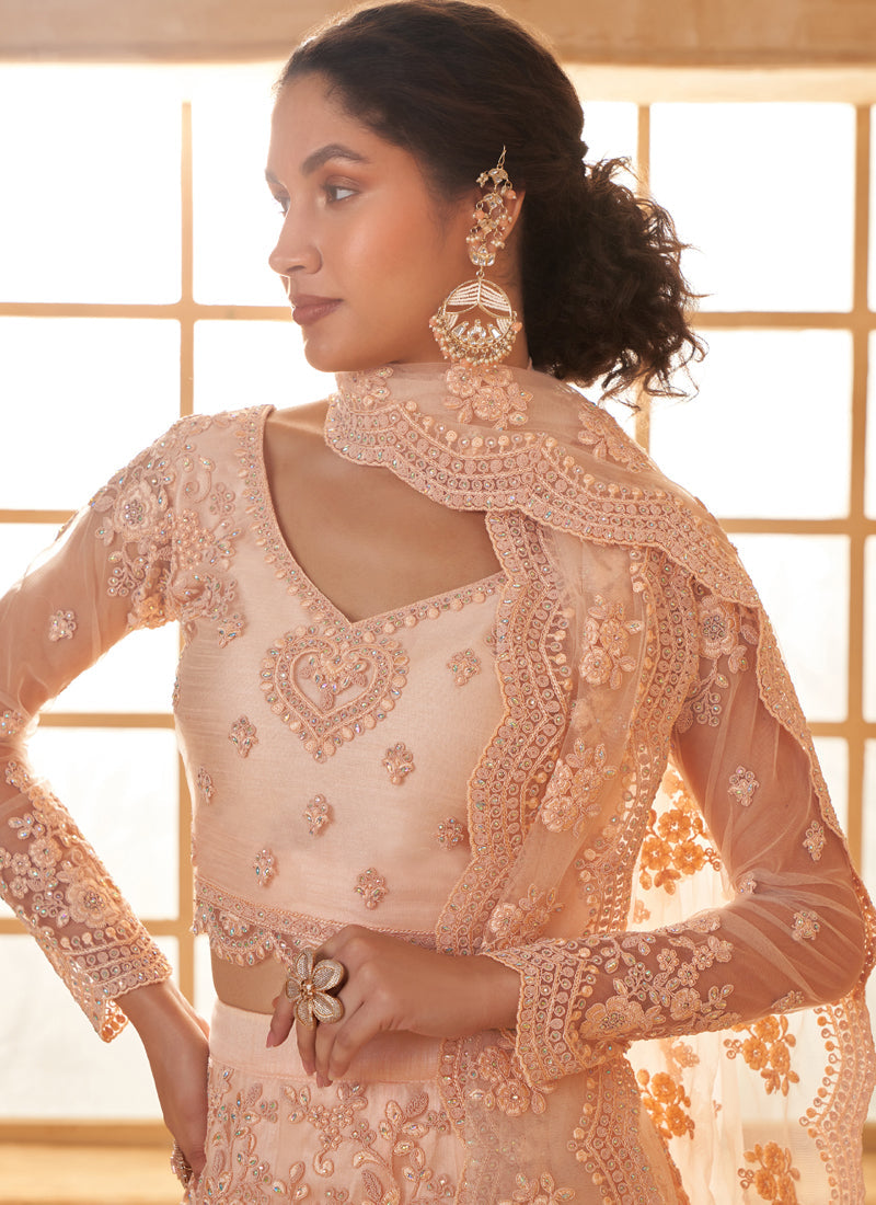 Woman wearing a cream net lehenga choli with intricate thread work embroidery