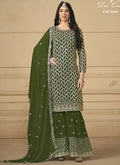 Woman wearing a Mehendi green anarkali sharara suit with metallic gold embroidery and mirror work.