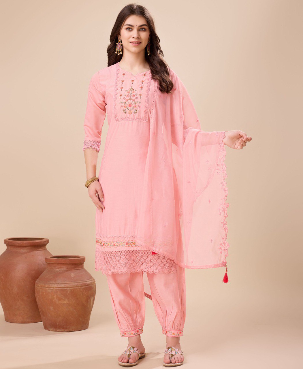 A woman wearing a peach viscose silk embroidered kurta set with an Afghani salwar and matching dupatta.