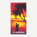 A colorful beach towel depicting a couple in silhouette under palm trees during a vibrant Florida sunset.