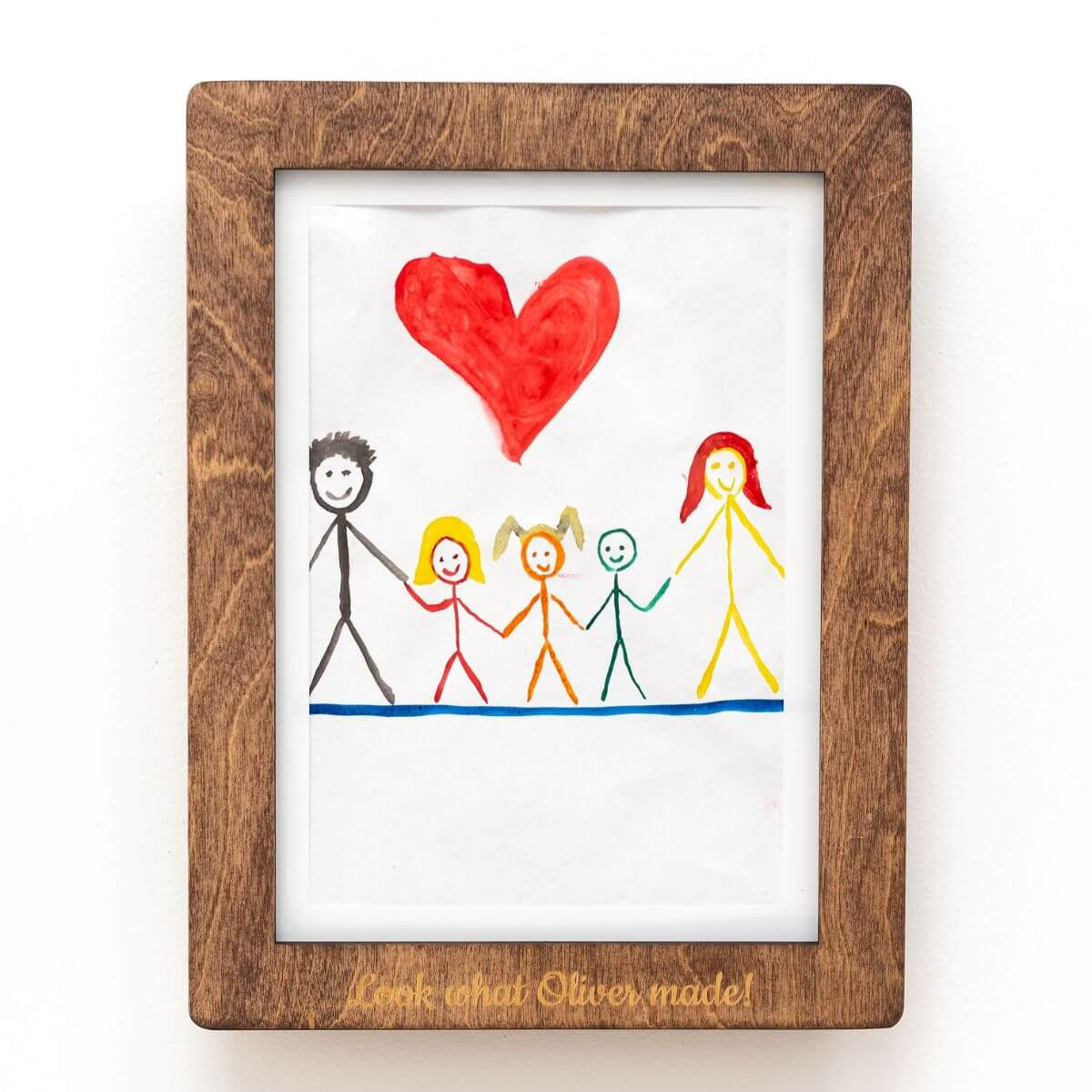 A modern natural wood artwork frame displaying children's art on a minimalist living room wall.
