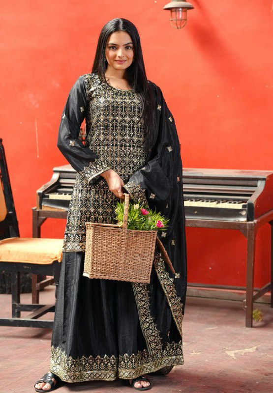 Model wearing a black Chinon silk sharara suit with intricate sequence embroidery and matching flared pants.