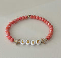 Love Red Glass Bead Bracelet featuring alternating red glass beads and gold cross charms.