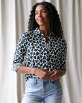 Model wearing a black and white heart print button-down shirt with a classic collar
