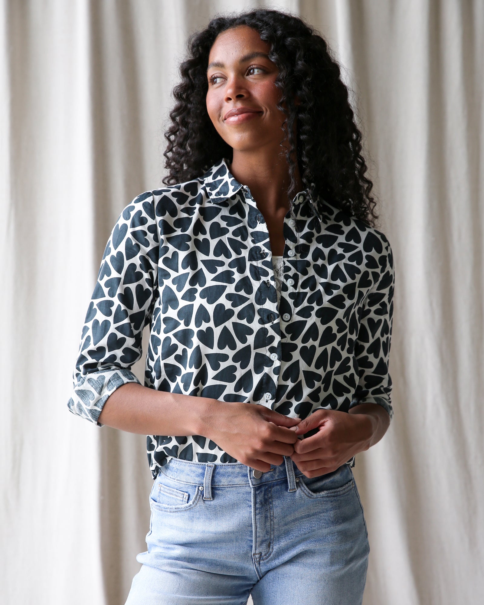 Model wearing a black and white heart print button-down shirt with a classic collar