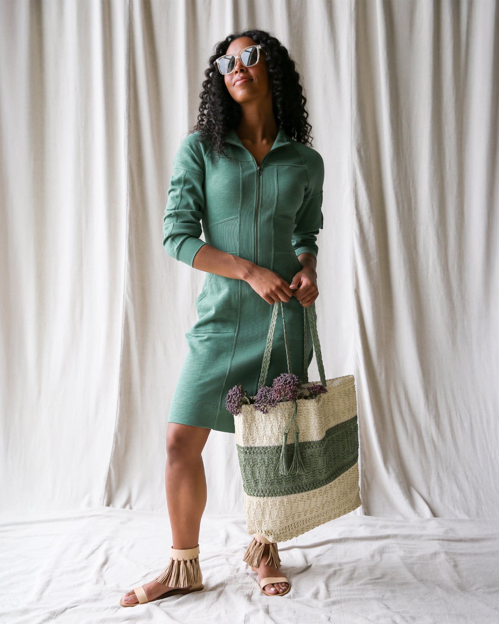 Model wearing a green long sleeve fit and flare dress with a zip front and front pockets.