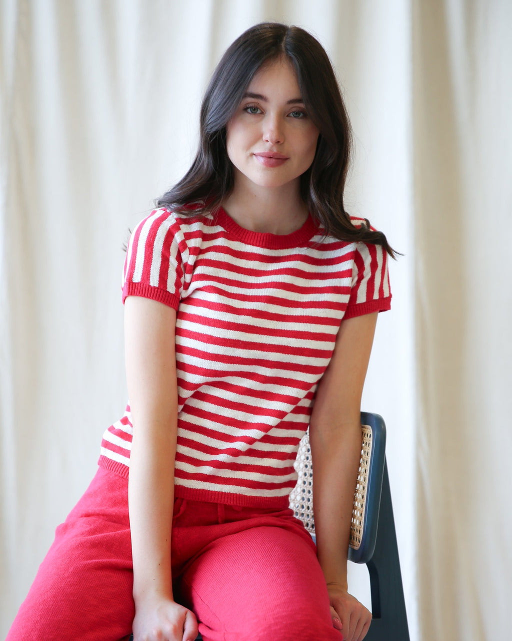 Woman wearing a red and white striped short-sleeve knit crewneck pullover with a relaxed fit