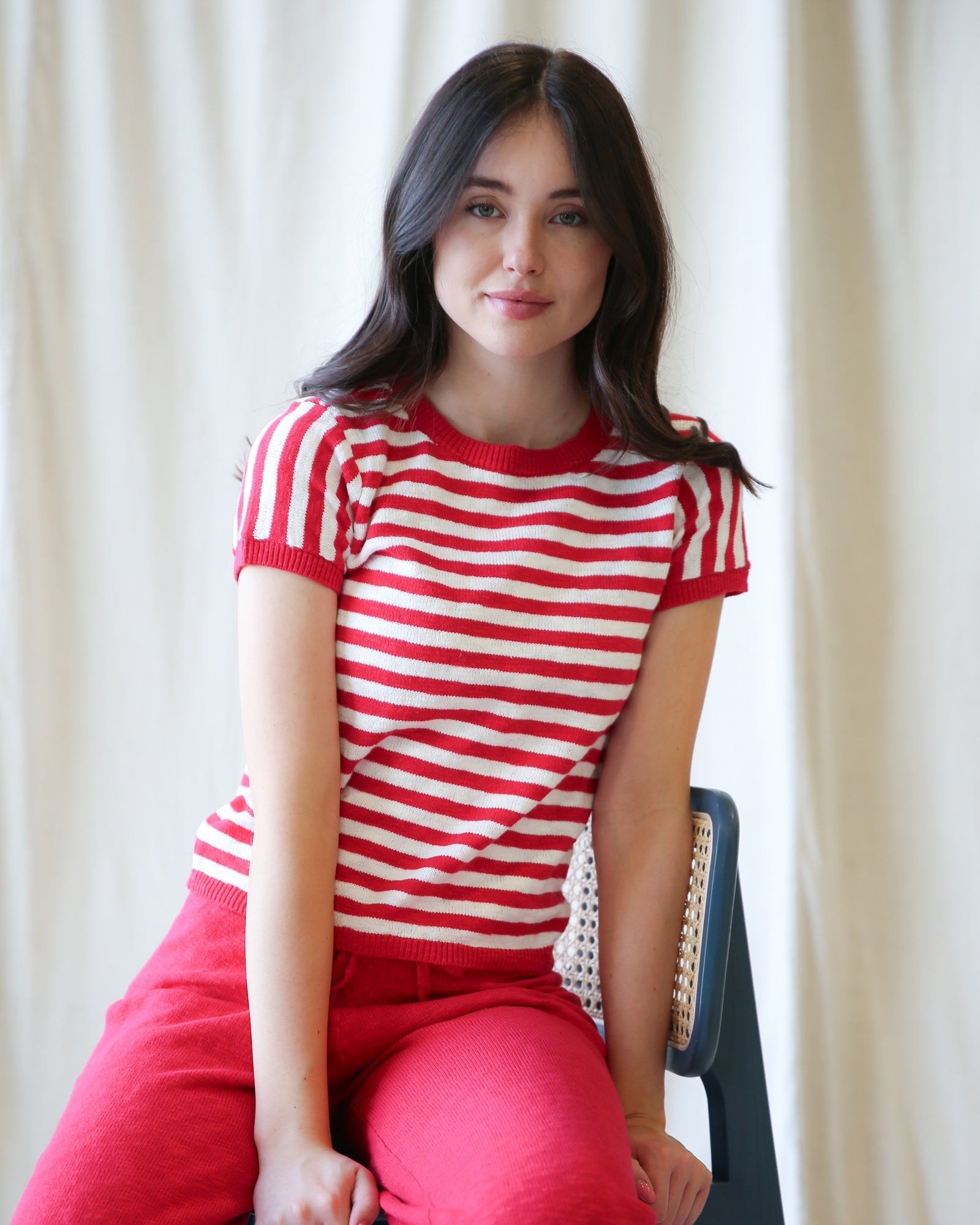 Woman wearing a red and white striped short-sleeve knit crewneck pullover with a relaxed fit