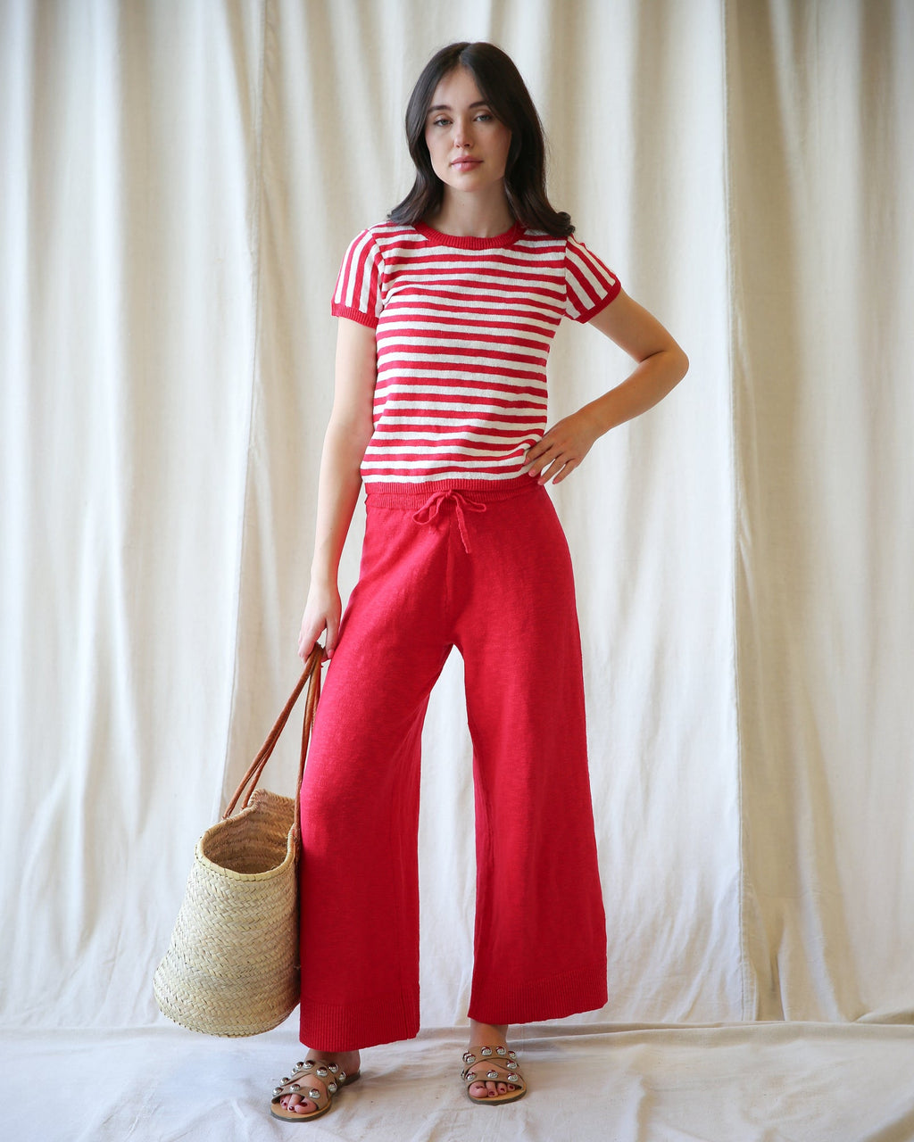 A woman wearing vibrant red, high-waisted wide-leg knit pants with a relaxed cropped fit.