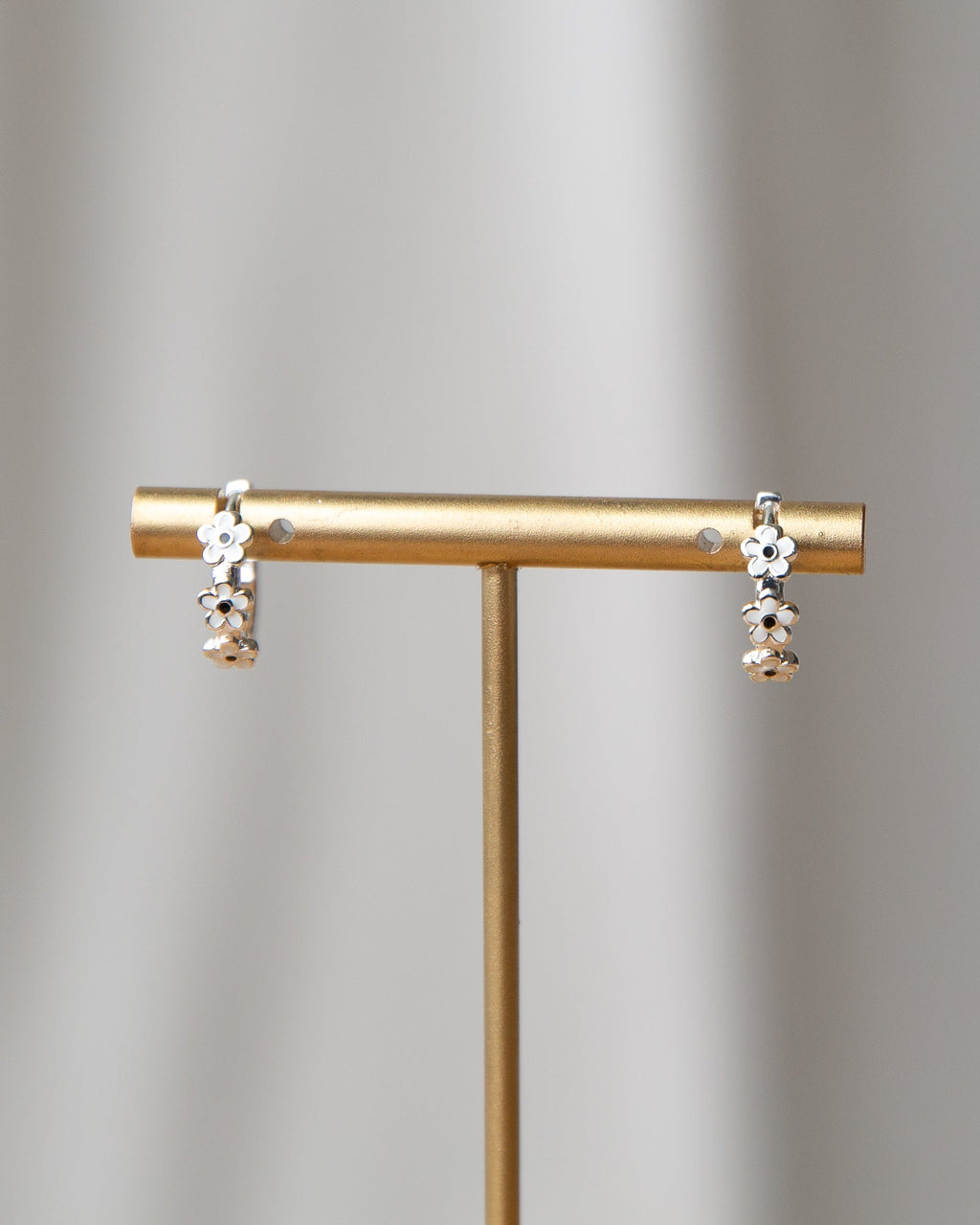 Silver In Bloom huggie hoop earrings featuring dainty white enamel flowers on a silver-plated hoop.