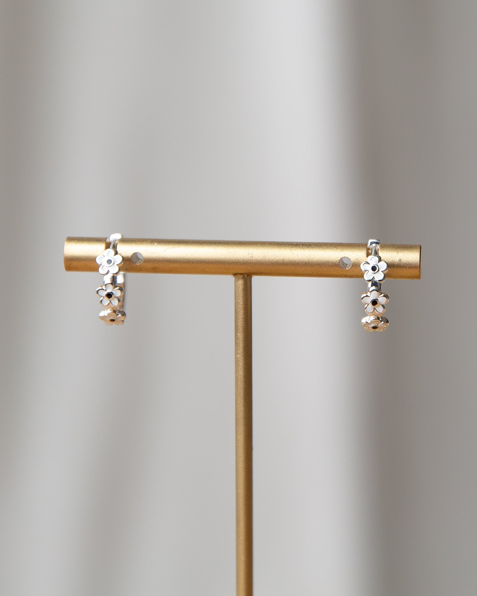 Silver In Bloom huggie hoop earrings featuring dainty white enamel flowers on a silver-plated hoop.