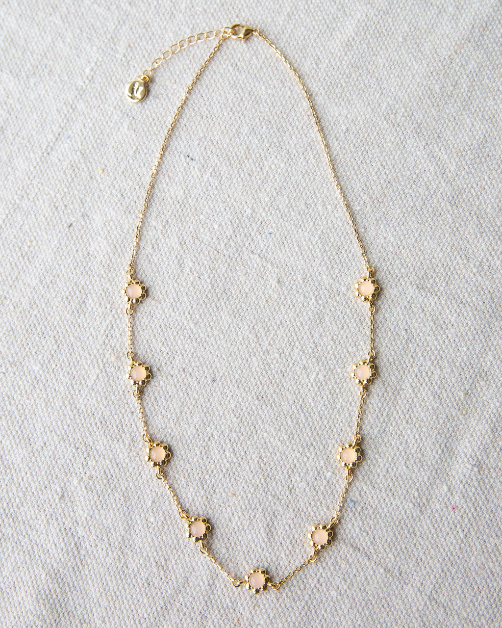 Mini flower necklace with a rose quartz colored glass stone on a 14K gold-plated cable chain.
