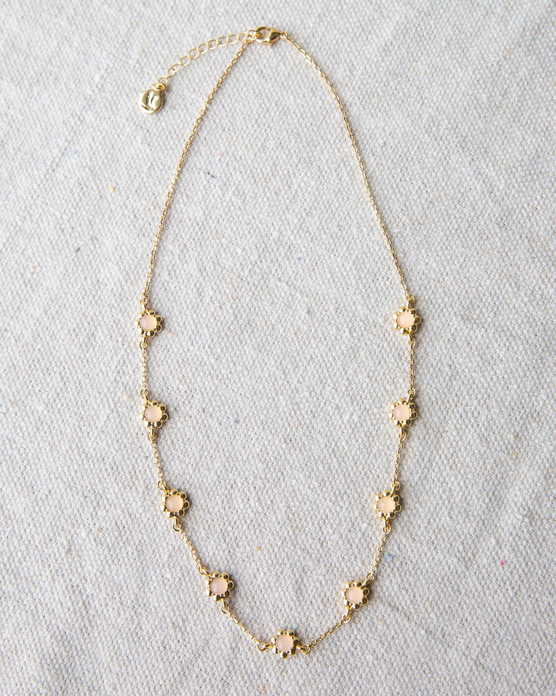 Mini flower necklace with a rose quartz colored glass stone on a 14K gold-plated cable chain.