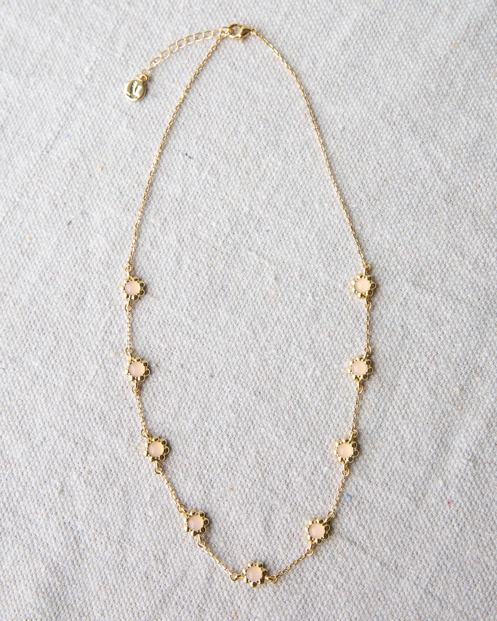 Mini flower necklace with a rose quartz colored glass stone on a 14K gold-plated cable chain.