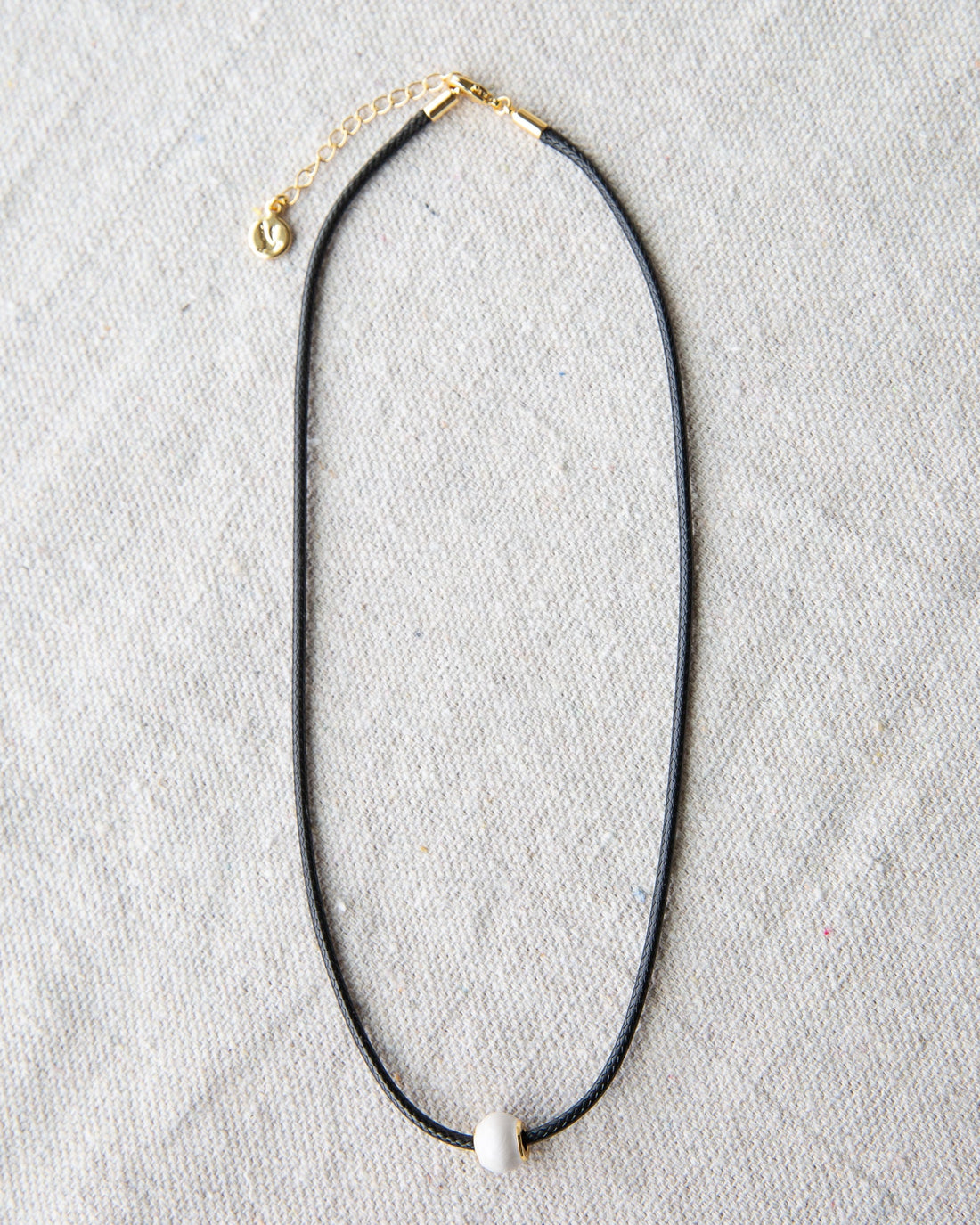Minimalist dark brown cord choker necklace with a round glass pearl and gold-plated accents